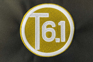 T6 point 1 embroidered circle logo with white text over a yellow background