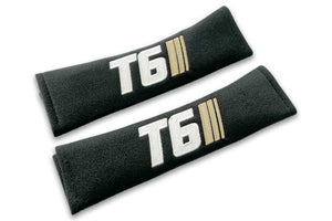 T6 Stripes logo embroidered on padded seat belt covers shown in black with white and cream embroidery.