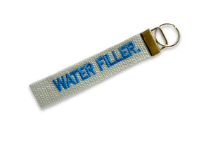 Grey fabric key ring with water filler embroidered in blue.