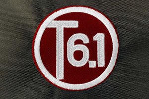 T6 point 1 embroidered circle logo with white text over a burgundy background