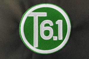 T6 point 1 embroidered circle logo with white text over a green background