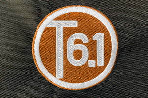 T6 point 1 embroidered circle logo with white text over a orange background