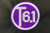 T6 point 1 embroidered circle logo with white text over a purple background