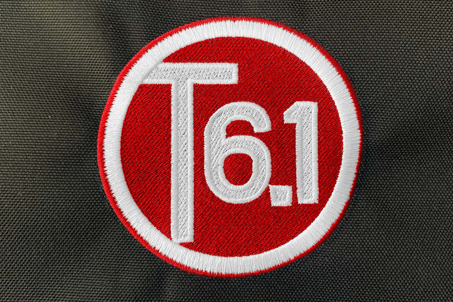 T6 point 1 embroidered circle logo with white text over a red background